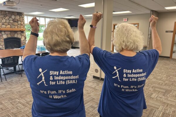 Trained volunteer leaders Elaine and Carolyn show off the back of their blue shirts.