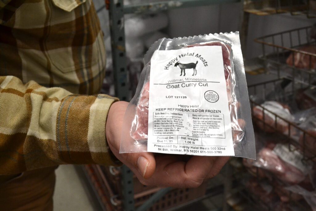 A sealed plastic package of goat meat with the Happy Halal Meats logo on a white label.
