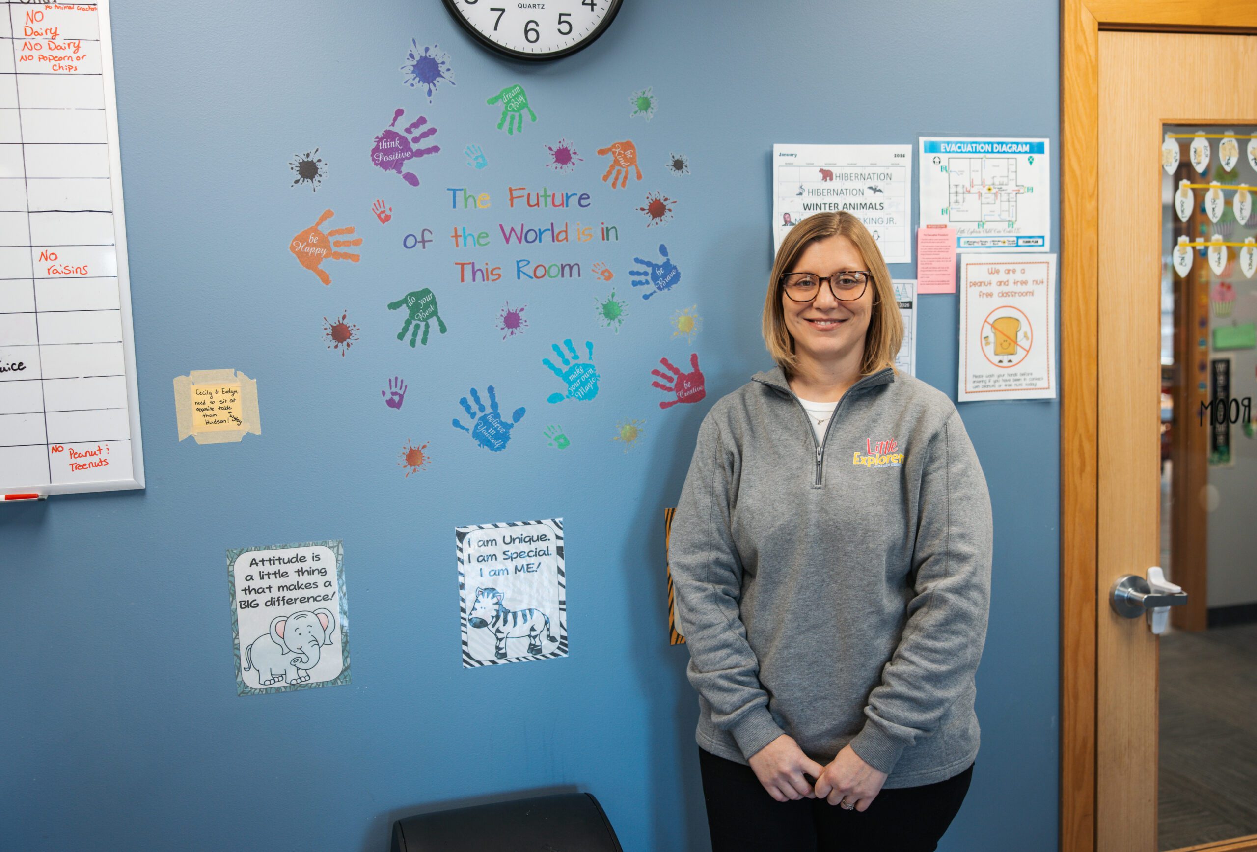 Jamie Gillund stands near a decorative wall display that says,"The future of the world is in this room" at Little Explorers Child Care Center in Ghent.